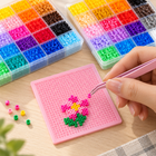 Illustrative making scene: placing mini fuse beads on a pink pegboard