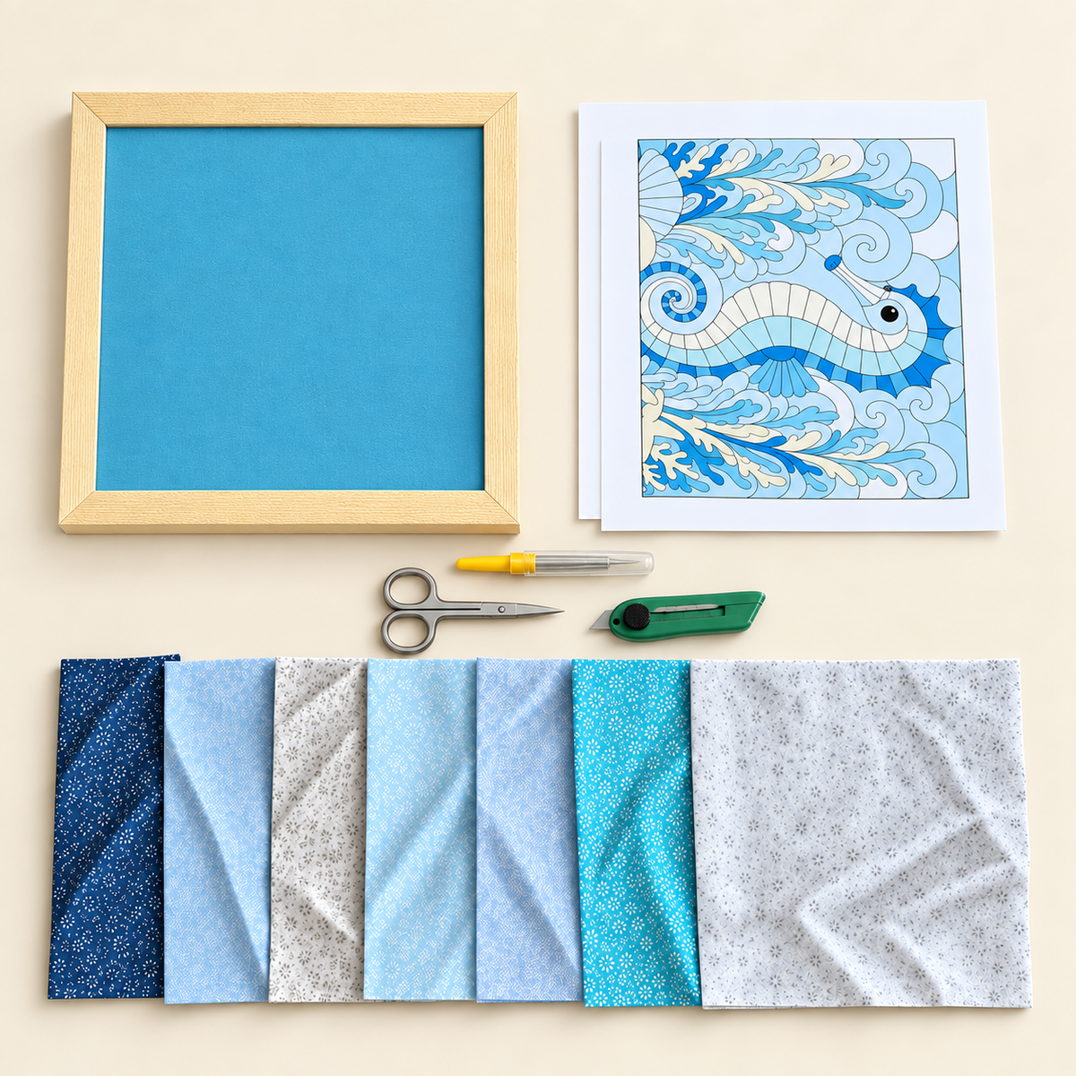 Kinusaiga kit contents laid out flat: a framed board, a printed pattern sheet, a fabric tucking tool, scissors, a craft knife and pieces of fabric